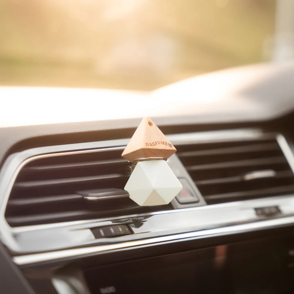 Car air freshener hanging from a car's air vent with a blurred background