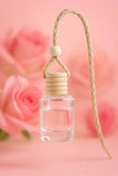 Clear car air freshener with wooden beads on a pink background