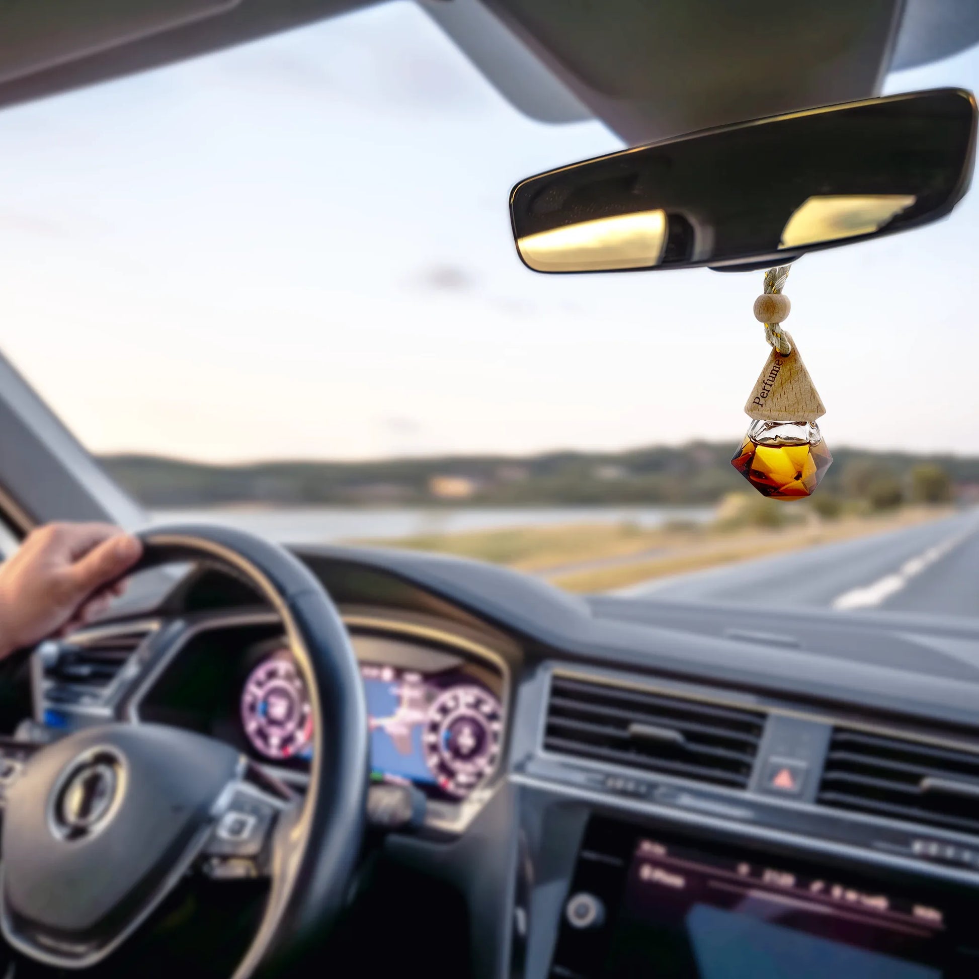 Car interior with a dashboard view, steering wheel, and rearview mirror with a decorative hanging charm.